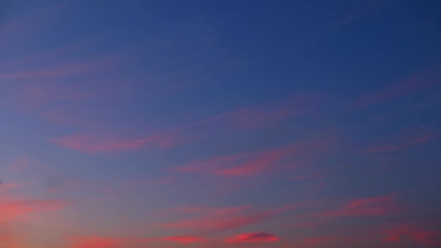 A sunrise sky timelapse video capturing thin cirrus clouds painted with gentle orange and pink tones as daylight emerges, revealing high-altitude cloud movement and tranquil morning atmosphere. 4k.
