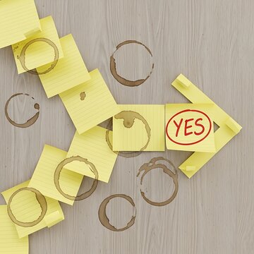A collection of yellow sticky notes with one note featuring a red YES in a circle is arranged on a wooden surface surrounded by coffee rings.