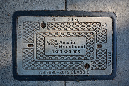 Concrete Aussie Broadband communication pit cover, featuring the internet service provider's logo and phone number