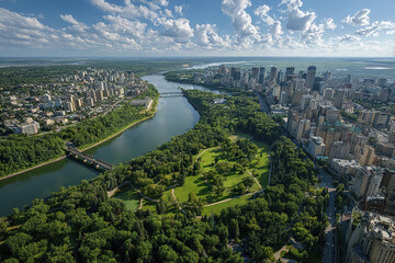 Aerial panoramic view of city skyline with river, bridges, and green parkland under blue sky with scattered clouds, showing urban and natural landscape harmony