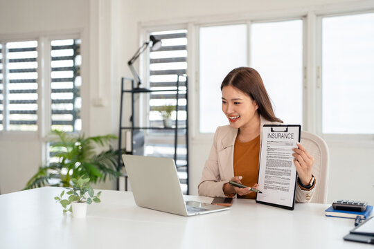 Young asian business woman talking with client online presents insurance contract , sitting in front of laptop, female officer working remotely from office.