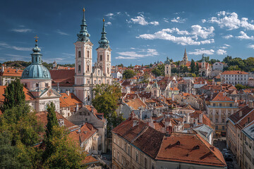 Obraz premium Historic European skyline panorama with domed churches and red rooftops under bright blue sky with scattered clouds, evoking peaceful and timeless atmosphere