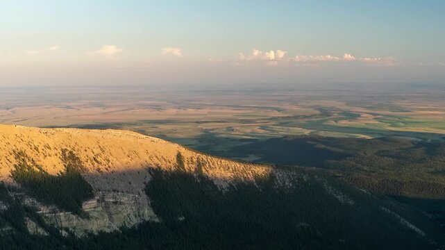 Evening shadow creeping up a mountain ridge above the plains as pink clouds glow and fade to night, Big Snowy Mountains, Montana, time lapse