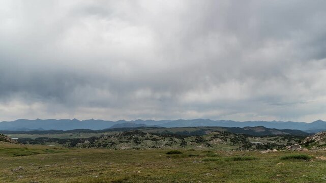 Overcast clouds moving over green alpine tundra and distant mountain ranges on the Beartooth Plateau, Montana, time lapse