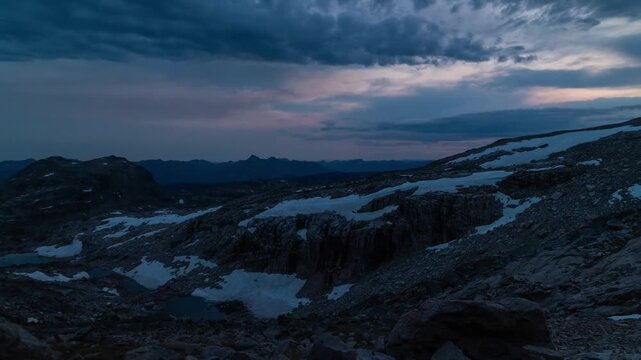 Dusk clouds moving over snow patches and rocky alpine terrain as light fades to night, Beartooth Plateau, Montana, time lapse