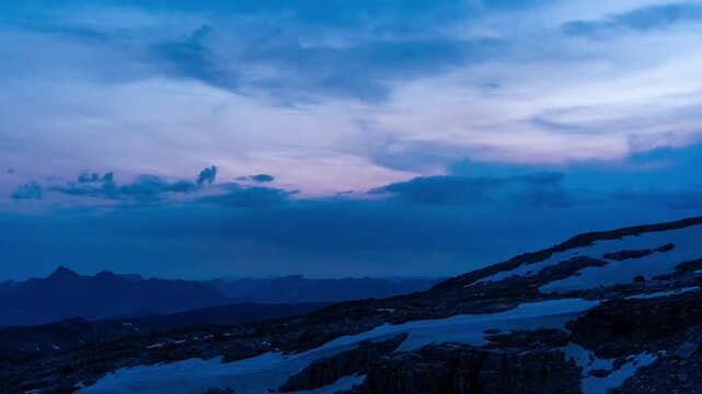 Pink sunset clouds fading to night over snowfields and rocky ridges on the Beartooth Plateau, Montana, time lapse