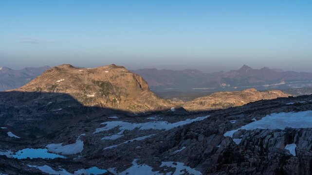Morning sunlight spreading and shadows retreating across rocky alpine terrain and snow patches, Beartooth Plateau, Montana, time lapse