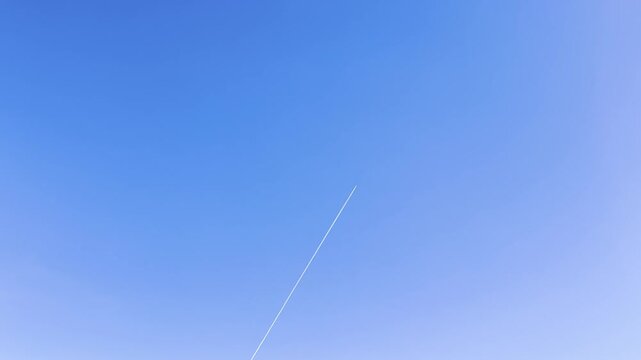 Jet trail against clear blue sky, minimalist air travel concept with space for text