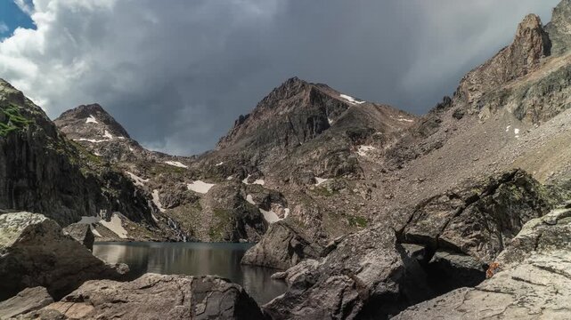 Storm clouds building over an alpine lake below jagged peaks and granite boulders near Granite Peak, Montana, time lapse