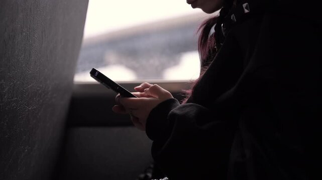 Close up view of Student sitting in school bus seat using smartphone while traveling to or from school.