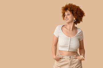 Stylish redhead young woman with curly hair on beige background