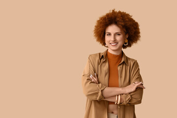 Redhead young woman with curly hair in shirt on beige background