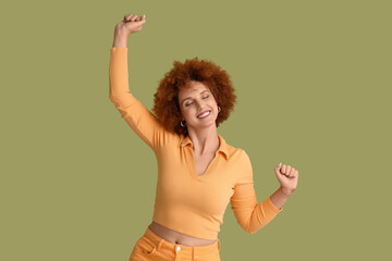 Happy redhead young woman with curly hair on green background
