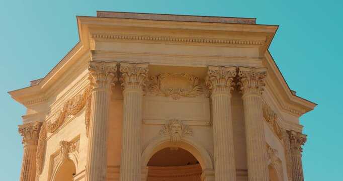 Peyrou Water Tower stands in Montpellier, France. The structure showcases classic architecture against a clear blue sky, with viewers appreciating its grandeur.