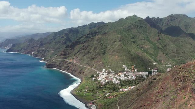 Aerial view flying over the scenic coastal town of Igueste de San Andres in Tenerife, Canary Islands, with waves crashing on the beach