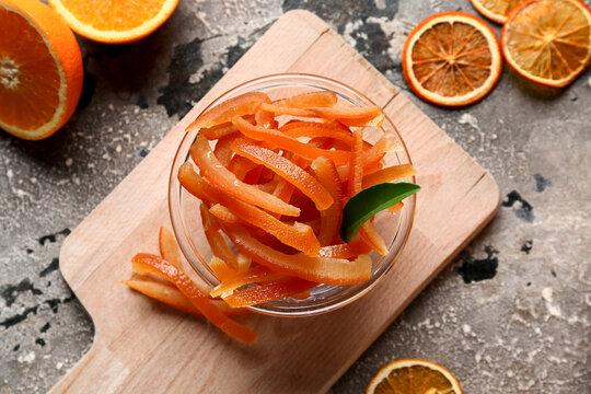Bowl with candied orange peel and dried slices on grey grunge background