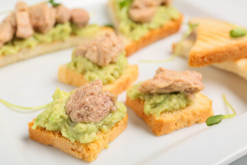 Delicious sandwiches with cod liver and avocado on plate, closeup