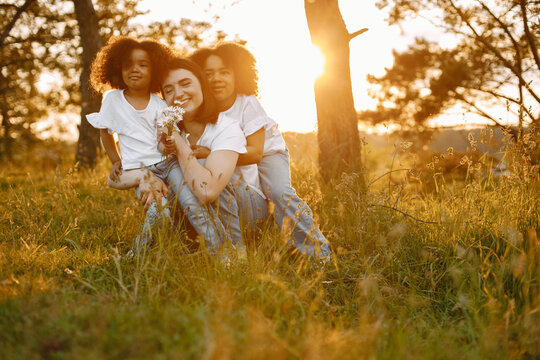 Caucasian mother embracing her two mixed race daughters in a sunset