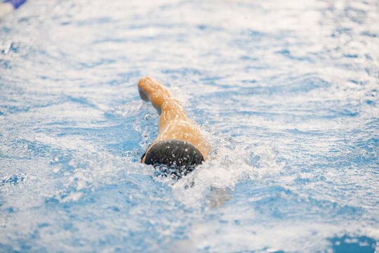 Man an in hat swimming in indoors swimming pool breaststroke