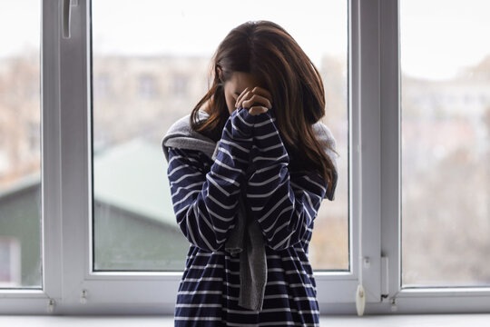 Upset young Asian woman near window at home. International Stress Awareness Week