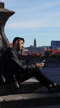 Young man texting on phone with scenic European city background