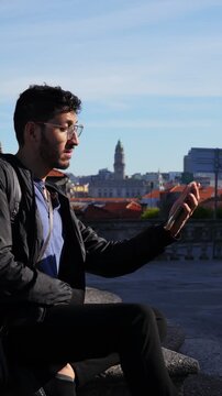 Man checking phone while sitting on historic viewpoint