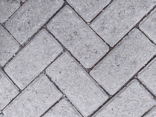 Obraz premium The road surface texture consists of paving blocks (precast concrete blocks) arranged in a herringbone pattern at an angle of either 45 or 90 degrees, allowing the blocks to interlock with one another