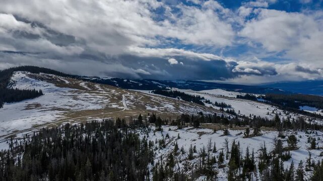Hyperlapse of clouds moving over snowy forested ridges and open slopes in the Gravelly Range, Montana