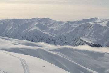 Snow covered mountain range extends into the distance under overcast sky
