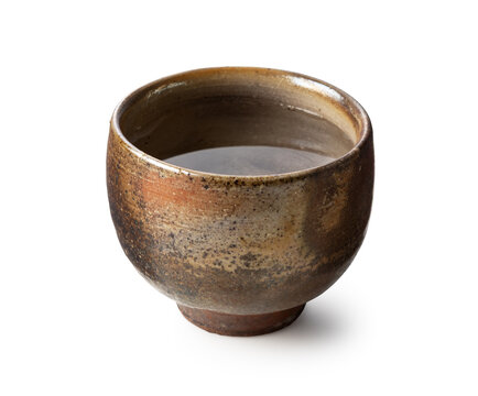 Traditional Japanese Bizen ware ceramic sake cup filled with sake isolated on white background