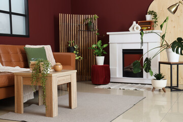 Naklejka premium Interior of stylish living room with cozy brown sofa, wooden coffee table and fireplace