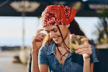 Lifestyle woman with modern boho-western denim street style smiling happily while holding a drink,...