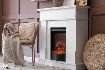 Naklejka premium Fireplace with armchair and decor near brown wall in living room