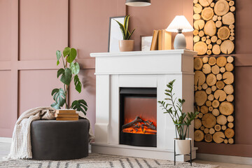 Naklejka premium Interior of cozy room with glowing lamp, pouf and stylish fireplace