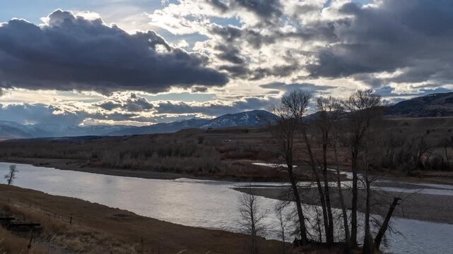 Dramatic clouds and sunset light over the Yellowstone River and bare cottonwoods, fading to blue dusk, Paradise Valley, Montana, time lapse