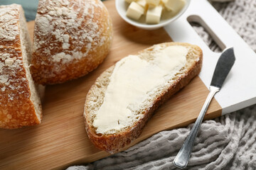 Slice of fresh bread with butter on wooden board, closeup