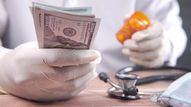 Medical professional in white gloves holding wad of hundred dollar bills with medicine bottle and stethoscope
