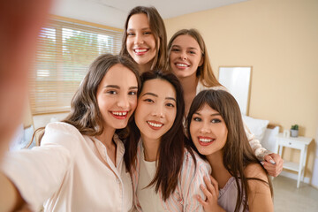 Obraz premium Group of young women taking selfie at Hen Party in bedroom