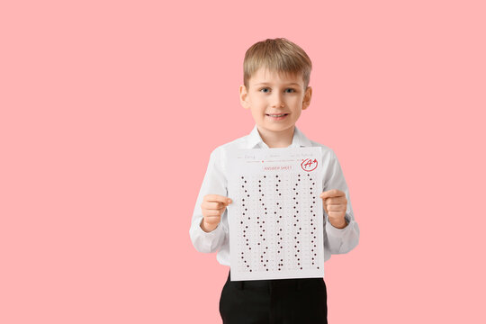 Happy schoolboy with good results of school test on pink background