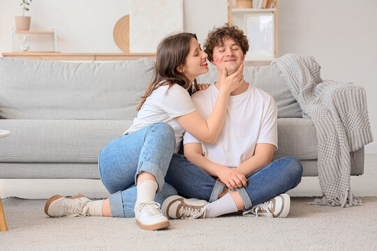Young woman and her boyfriend with lipstick kiss marks at home