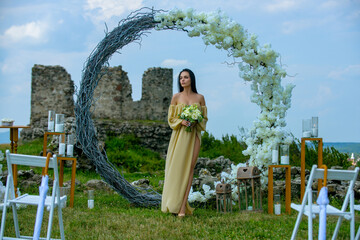 Naklejka premium Elegant bride woman under wedding arch. Romantic wedding arch outdoor scene. Bride under floral wedding decor. Luxury wedding arch with flowers. Beauty bride ceremony concept.