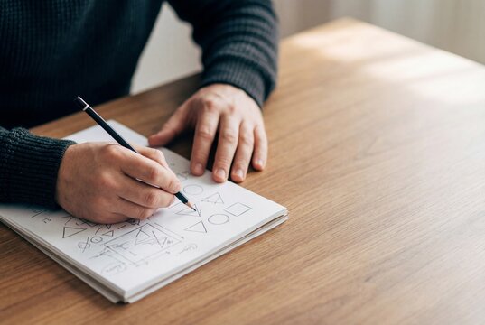 Hands solving math on paper with simple shapes