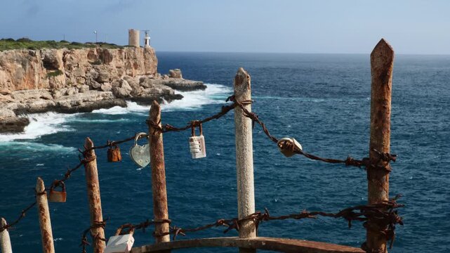 Love locks in Cala Figuera, with the Torre d'en Beu lighthouse in the background. Mallorca, Spain