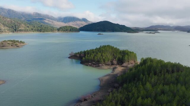 Forested peninsula at Aoos Springs Lake Techniti Limni Aoou Epirus Greece, aerial medium backdrop reveals shoreline and forested islands