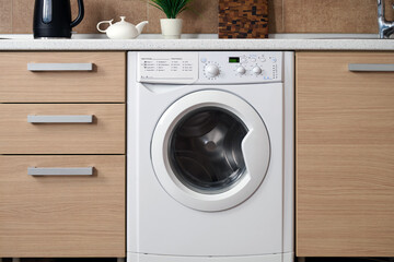 Modern kitchen in a minimalist style.The white washing machine is built into the kitchen front.