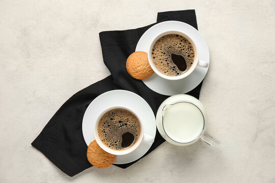 Cups of hot coffee with sweet cookies and jug of fresh milk on white background