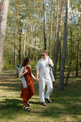 Fototapeta premium Couple enjoys a serene walk hand in hand through a lush forest on a sunny day