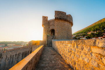 panorama of Dubrovnik's historic fortifications and old port at dusk, sunlight on ancient stone...