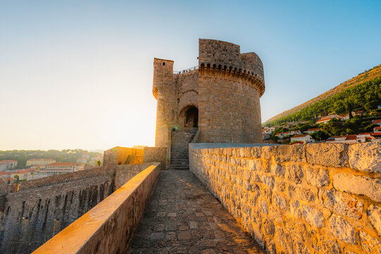 panorama of Dubrovnik's historic fortifications and old port at dusk, sunlight on ancient stone walls and Mediterranean architecture with Tvrdava Minceta