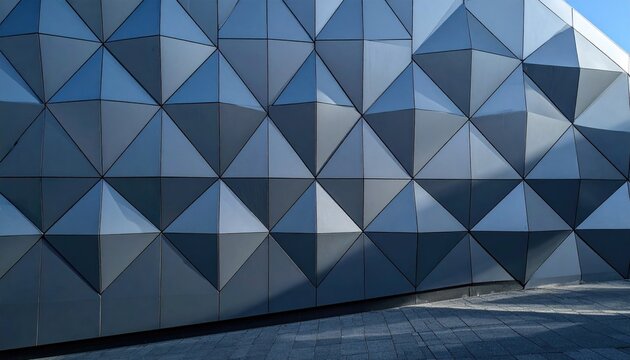 Angled triangles form a textured facade with shadows and sunlight, above gray stone pavers